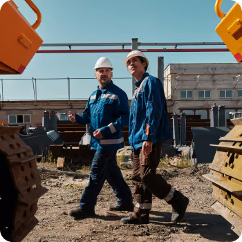 Two construction workers looking up at a construction site